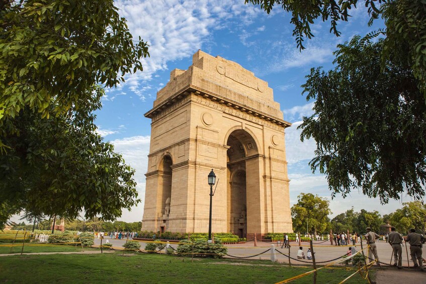 A large, historic stone monument with arches and inscriptions, surrounded by a well-maintained park with trees and pathways. 3