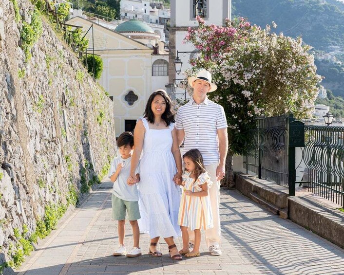 Une famille se promène sur un chemin de pierres, avec une église et des fleurs en pleine floraison en arrière-plan. 3