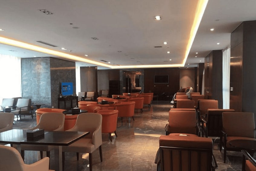 A modern lounge with orange seating, a TV, and a stone wall. 5