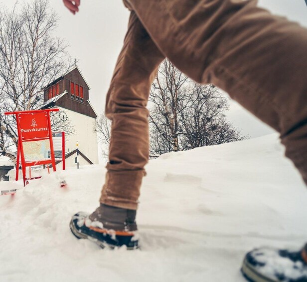 A person snowboarding on a snowy slope with a red sign in the background. 5