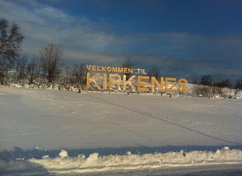 A snow-covered landscape with a sign reading 'VELKOMMEN TIL KIRKENES'. 2