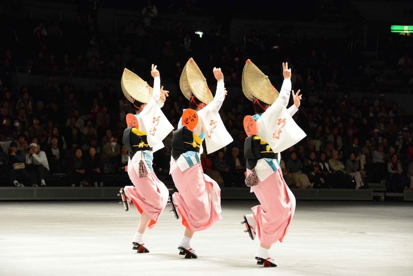 A traditional dance performance with dancers wearing white and pink costumes and conical hats. 1
