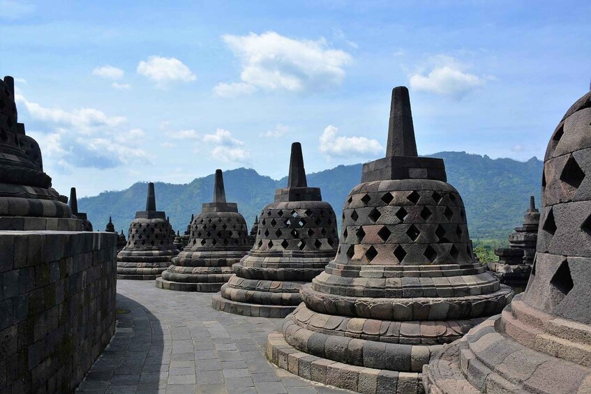 Stone stupas arranged in a row with a mountainous backdrop. 5