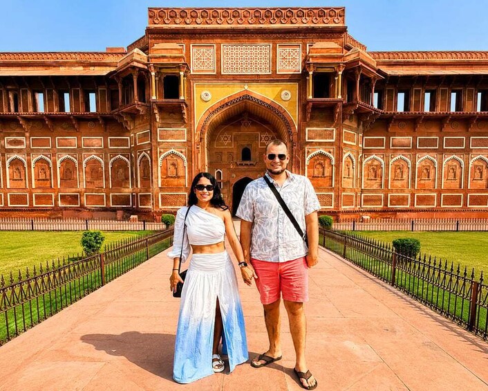 A couple standing in front of a large, ornate building with intricate architectural details. 4