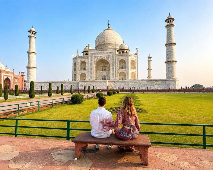 A couple sitting on a bench facing the Taj Mahal. 3