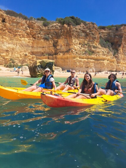 People kayaking on a clear day with rocky cliffs in the background. 3