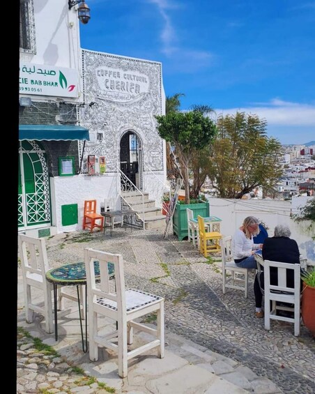 A café with outdoor seating, a sign reading "COFFEE CULTURAL CHERIA," and a view of the cityscape in the background. 1