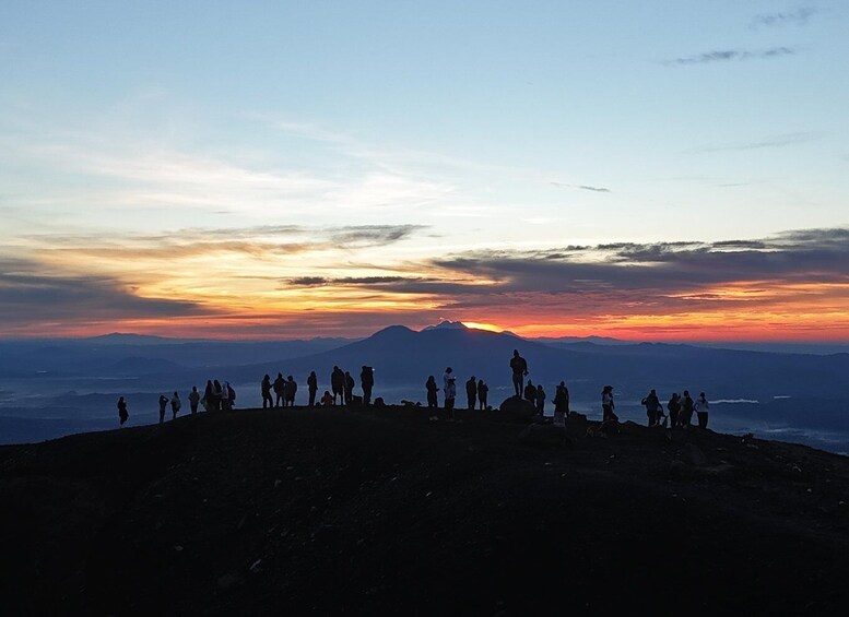A group of people standing on a mountain ridge at sunset. 1