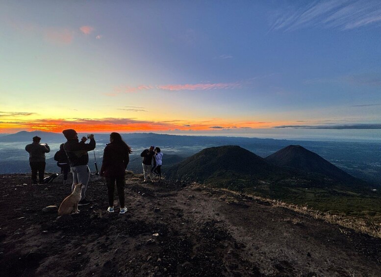 A group of people on a mountain ridge during sunset, taking photographs. 3
