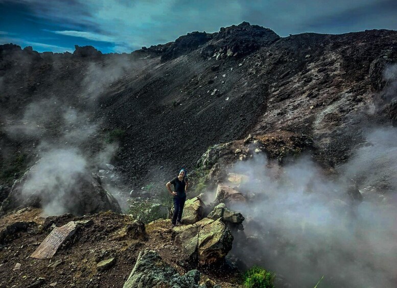 A person standing on a rocky mountain peak with steam rising from the ground. 5