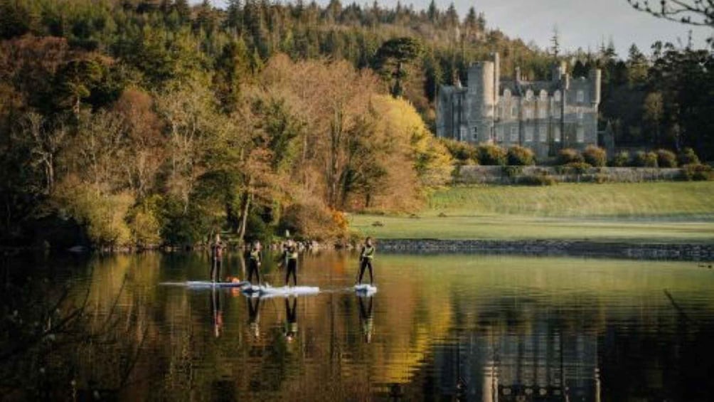 A group of people paddleboarding on a calm lake with a castle in the background. 2