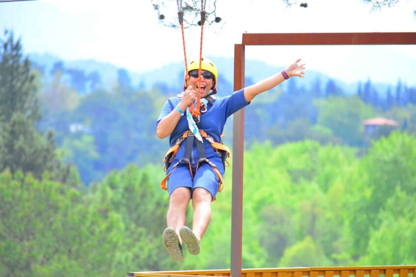 A person ziplining with safety gear, suspended above a forested landscape. 5