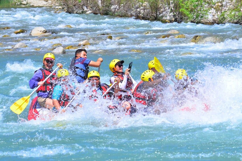 A group of people in a white raft navigating a river with rapids. 3