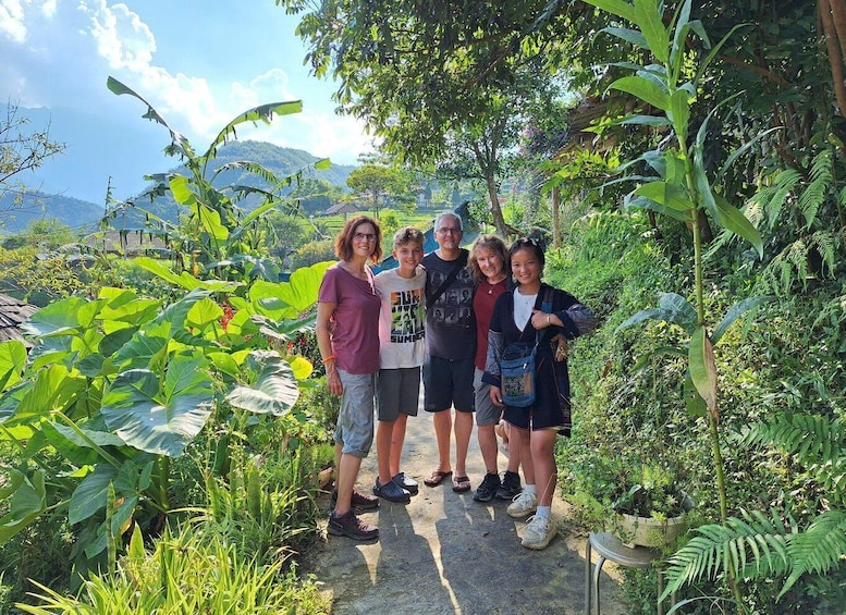 A group of people standing on a path surrounded by lush greenery and banana plants. 1