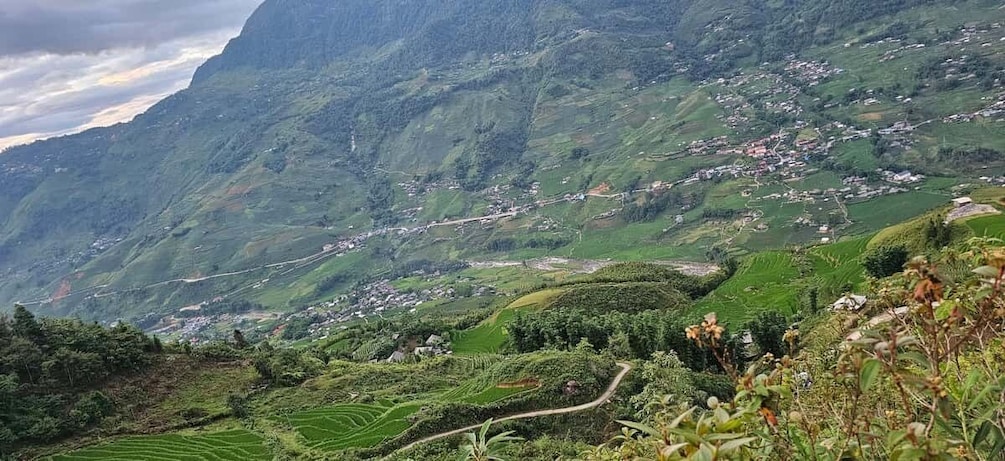 A mountainous landscape with terraced fields, a winding road, and a small village nestled in the valley. 3