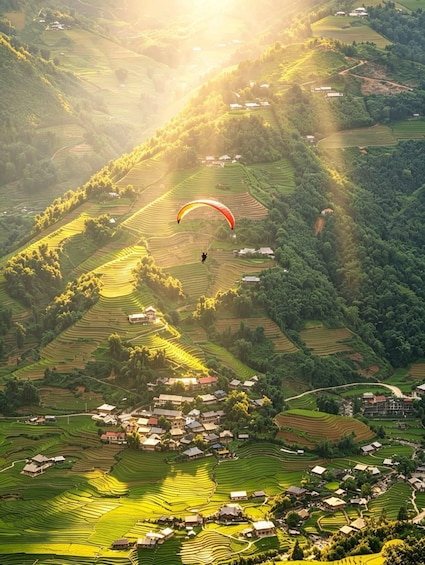 A person paragliding over terraced fields with a village below. 5