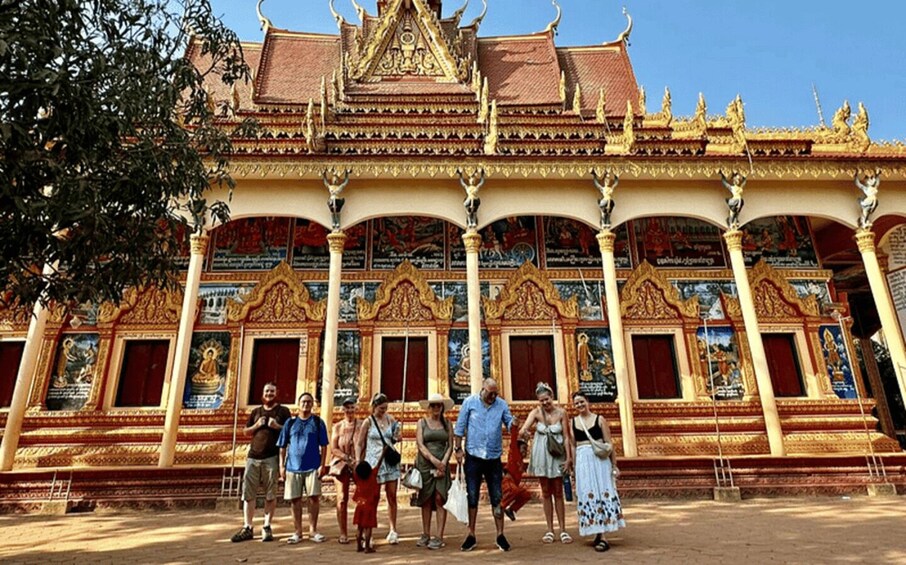 A group of people standing in front of a temple with ornate architecture and colorful murals. 2