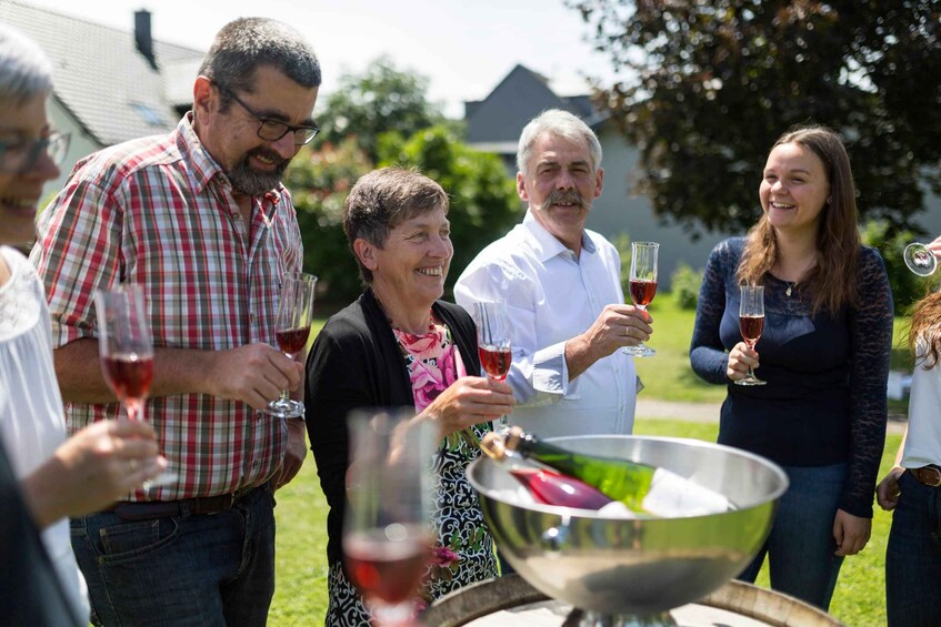 A group of people outdoors, some holding wine glasses, with a large metal bowl in the foreground. 5