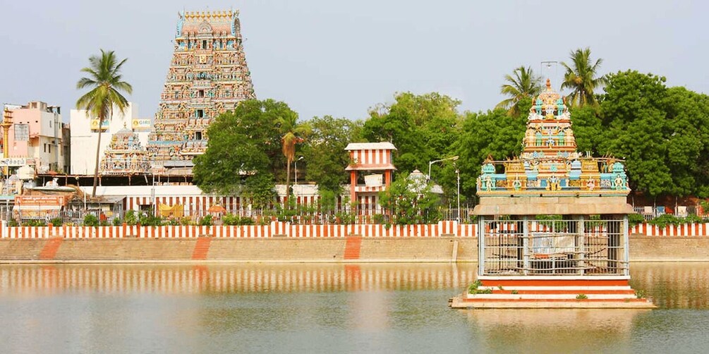 A temple with intricate architecture, a water body in the foreground, and a clear sky. 2