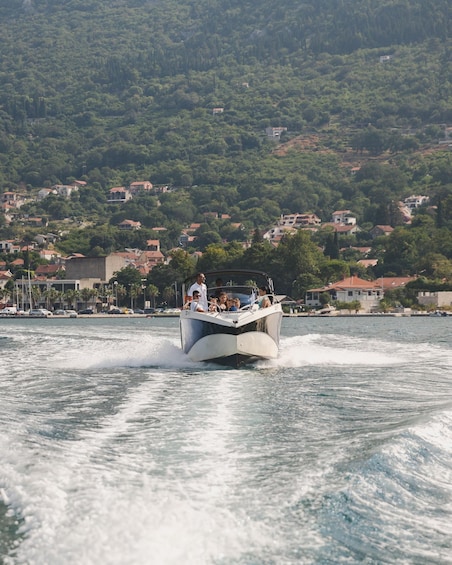 A speedboat with passengers on a lake, surrounded by houses and greenery. 3