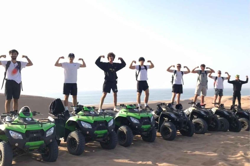 People standing on a beach with ATVs lined up in front. 1