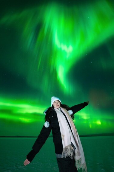 A person standing with arms outstretched under the Northern Lights. 5