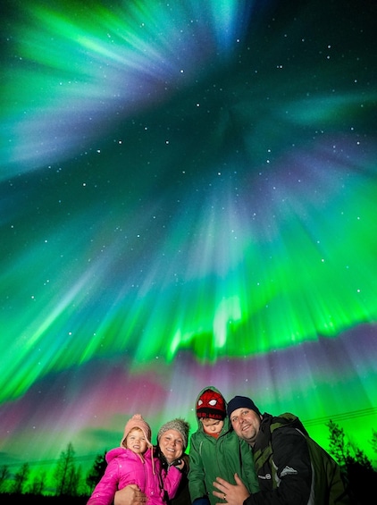 A family of four posing under the Northern Lights. 1