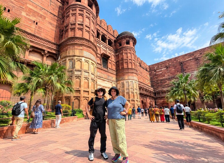 A historic building with intricate architecture, palm trees, and tourists. 5