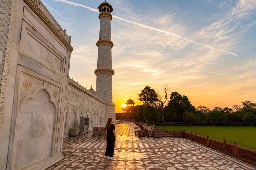 A historical building with intricate architecture, a tall tower, and a patterned courtyard. 2