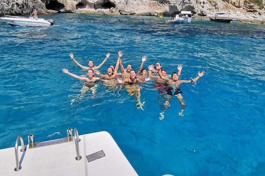 Un grupo de personas nadando en una piscina azul cristalina, con barcos al fondo. 2