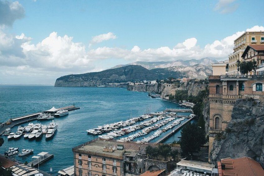 Un pueblo costero con un puerto deportivo, barcos y edificios a lo largo del acantilado. 3