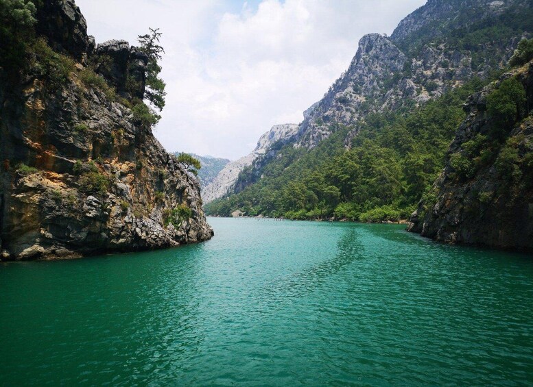 A turquoise river flanked by rocky cliffs and dense green foliage. 4