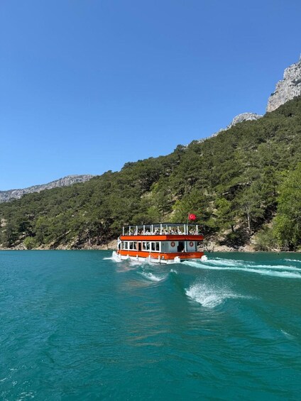 A boat named SEVINC 4 on a turquoise sea with a mountainous backdrop. 1