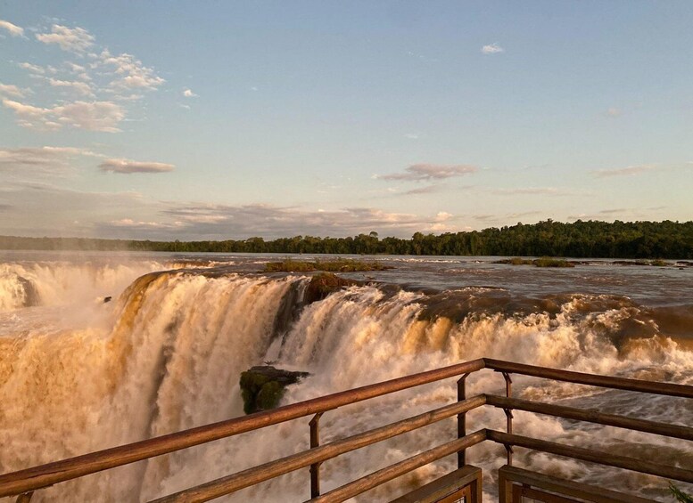 A waterfall with a wooden railing in the foreground. 4