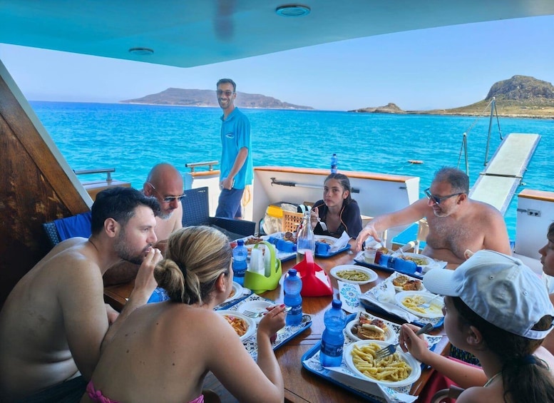 A group of people dining on a boat with a view of the sea and distant islands. 3