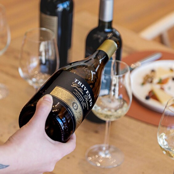 A person pouring wine from a bottle labeled 'TRIVENTO' into a glass. 3