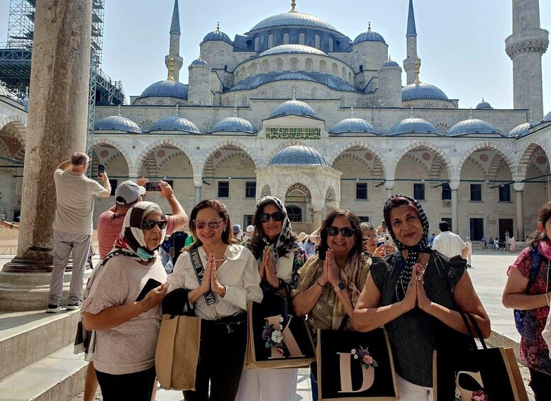 A group of people posing in front of a historic mosque with multiple domes and minarets. 1