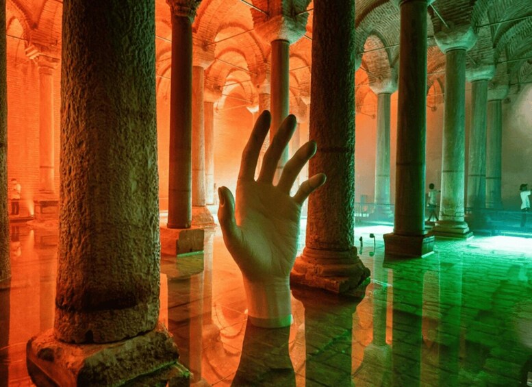 A hand reaching out towards a column in a dimly lit, ancient structure with arches and columns. 3