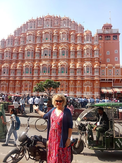 A woman in a floral dress standing in front of a large, ornate building with intricate architecture. 3