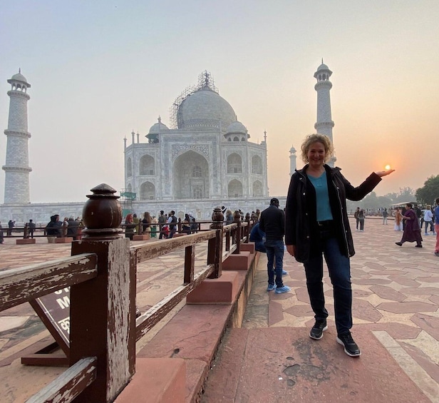 A person standing on a bridge with the Taj Mahal in the background. 1