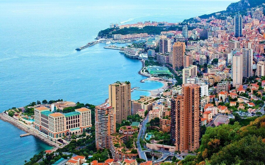A coastal cityscape with high-rise buildings, a marina, and a mountainous backdrop. 3
