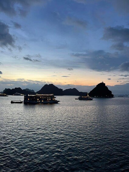 A calm body of water with two boats and a large island in the distance. 2