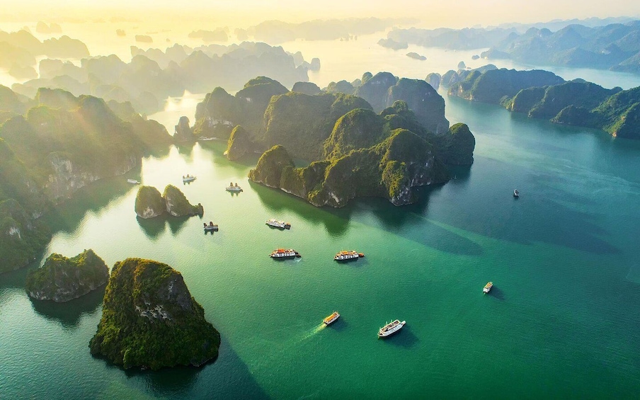 An aerial view of a coastal area with numerous boats on clear turquoise waters surrounded by lush green islands. 1