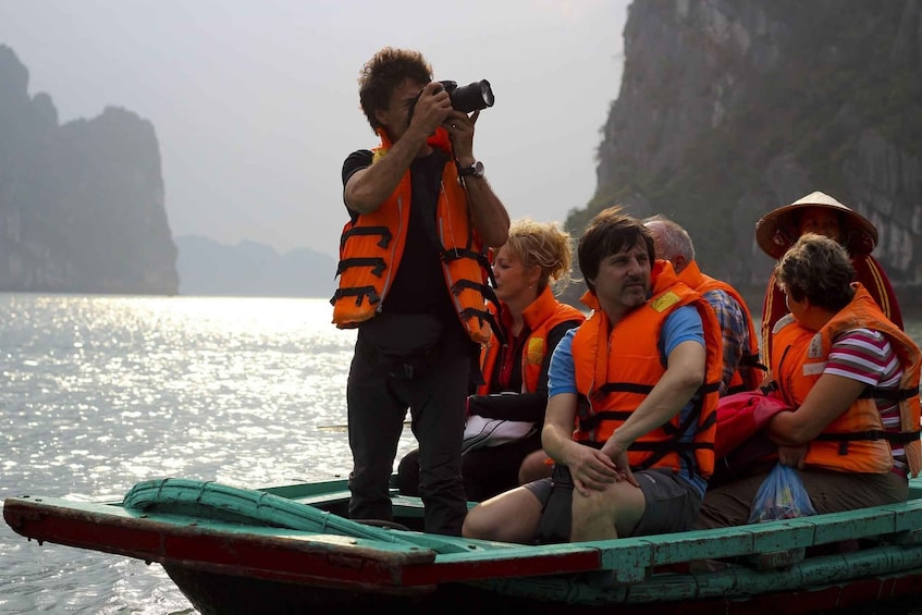A group of people in a boat wearing life jackets, with a person taking a photo. 3