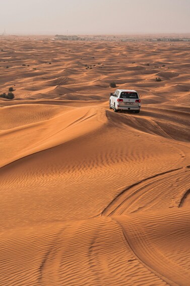 A white car driving through a desert with sand dunes. 3