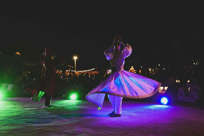 A person in a flowing dress performing on a stage with stage lights. 5