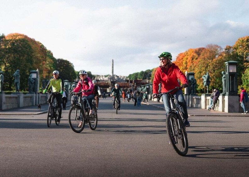 Cyclists on a bridge with autumn trees and a distant monument. 3