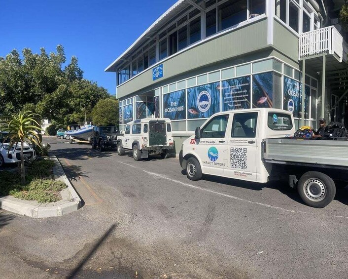 A building with 'The Ocean Hub' signage, parked vehicles, and a clear sky. 3
