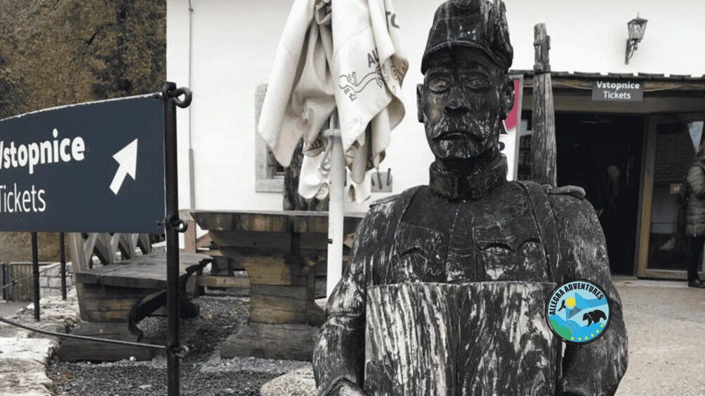 A statue of a man with a beard and a hat, a sign for 'Vstopnice Tickets', and a logo for 'ALLEGRA ADVENTURES'. 4