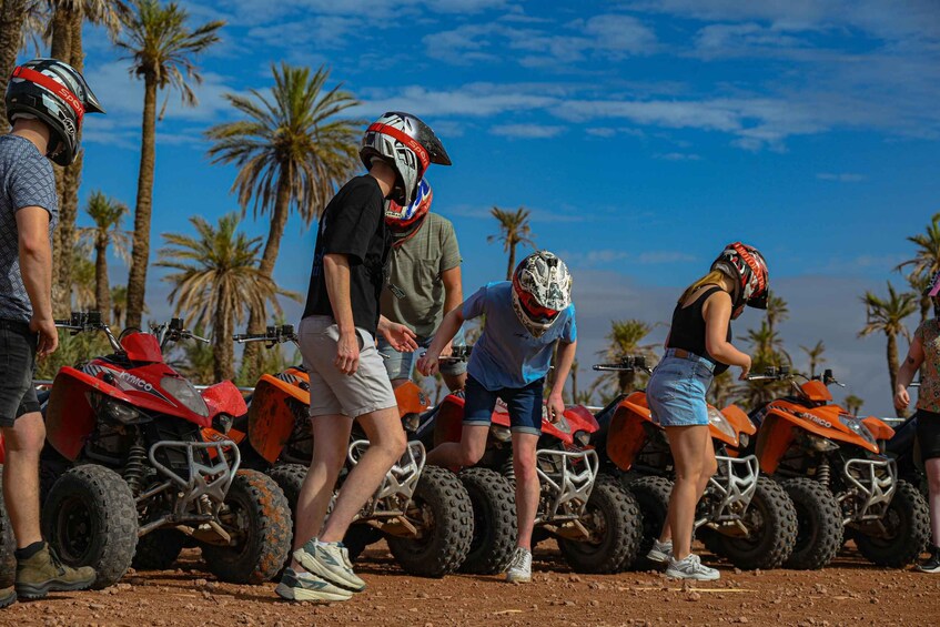 People standing around ATVs in a tropical setting with palm trees. 4